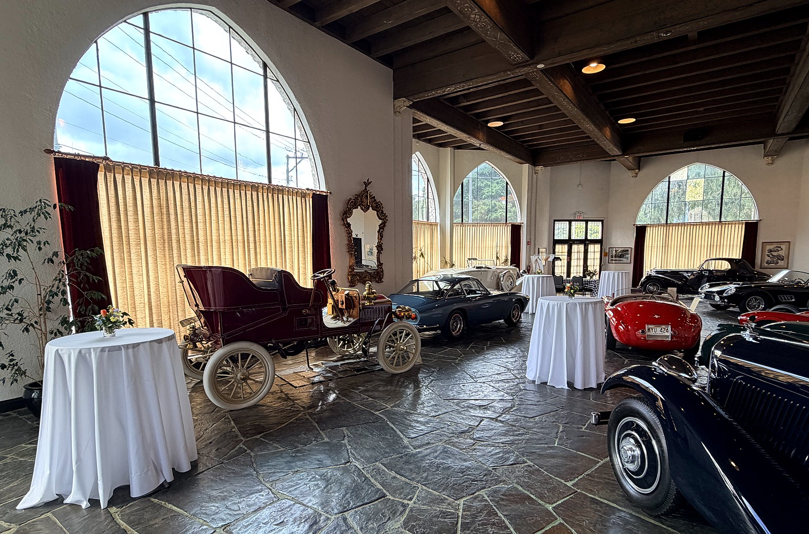 Linen cocktail tables among the collection beneath the arched windows